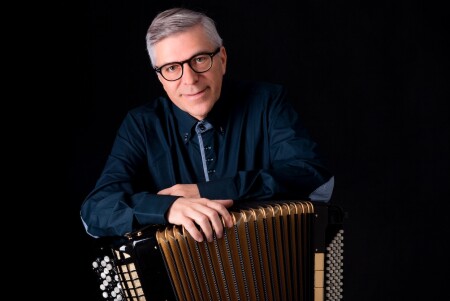 Porträt von Joseph Bachmann. Er sitzt auf einem Stuhl mit einem Akkordeon.