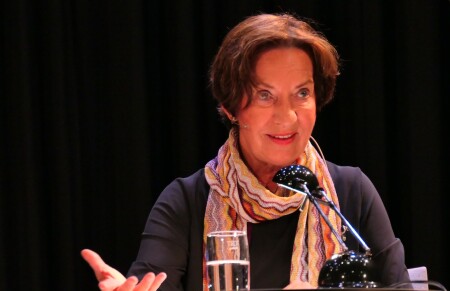 Porträt von Regina Bucher. Dunkles Haar, sie ist am sprechen.